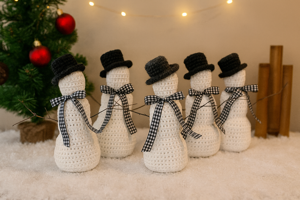 Five crocheted snowmen with top hats and checkered scarves in front of a Christmas tree.